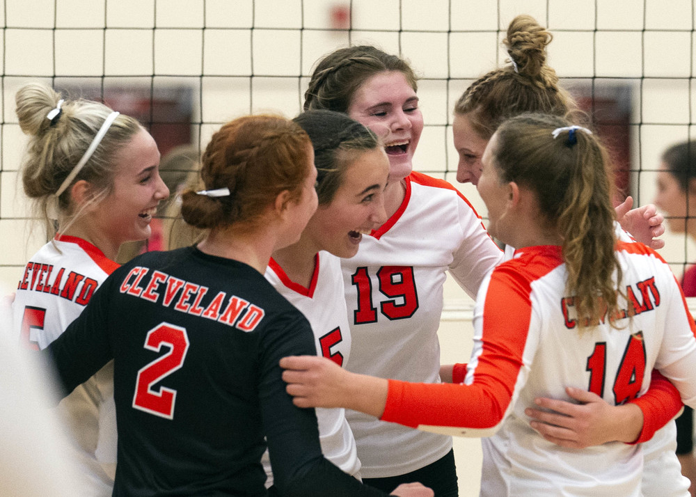 Members of the varsity girls volleyball team celebrate a point win